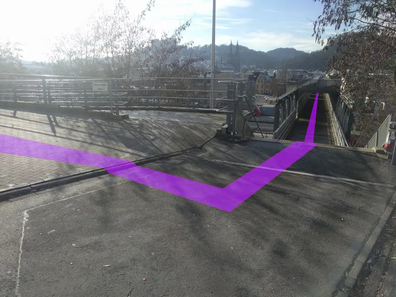 Am Ende der Überführung: ein violetter Streifen biegt nach rechts zur Treppe, im Hintergrund die Marburger Altstadt.